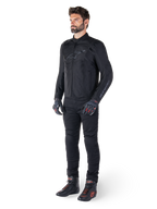 Veste Alpinestars T-SPS V2 Waterproof, noire, portée par un mannequin homme avec un pantalon noir assorti, des gants noirs avec des accents rouges et des chaussures de moto noires, équipement de moto complet pour la conduite urbaine et sportive, fond blanc