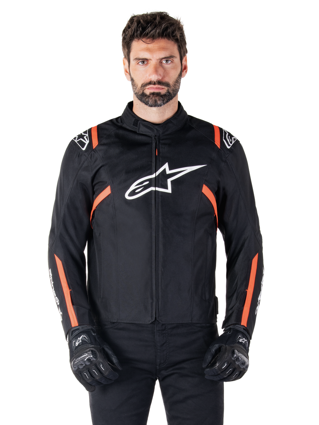 Veste imperméable Alpinestars T-SPS V2, noir, blanc et rouge fluo, portée par un mannequin homme avec des gants de moto noirs, avec un grand logo Alpinestars blanc sur la poitrine et des accents orange vif sur les épaules et les manches.