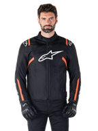 Veste imperméable Alpinestars T-SPS V2, noir, blanc et rouge fluo, portée par un mannequin homme avec des gants de moto noirs, avec un grand logo Alpinestars blanc sur la poitrine et des accents orange vif sur les épaules et les manches.