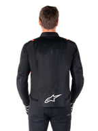 Veste imperméable Alpinestars T-SPS V2, noire avec accents blanc et rouge fluo, vue arrière présentant un grand logo Alpinestars blanc en bas du dos, veste de moto en textile coupe sport, portée avec un pantalon et des gants noirs