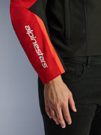Veste imperméable Alpinestars T-SPS V2, veste de moto, noir et rouge, gros plan de la manche présentant un logo de marque blanc vertical sur un empiècement rouge, construction en textile durable avec un design inspiré du sport.