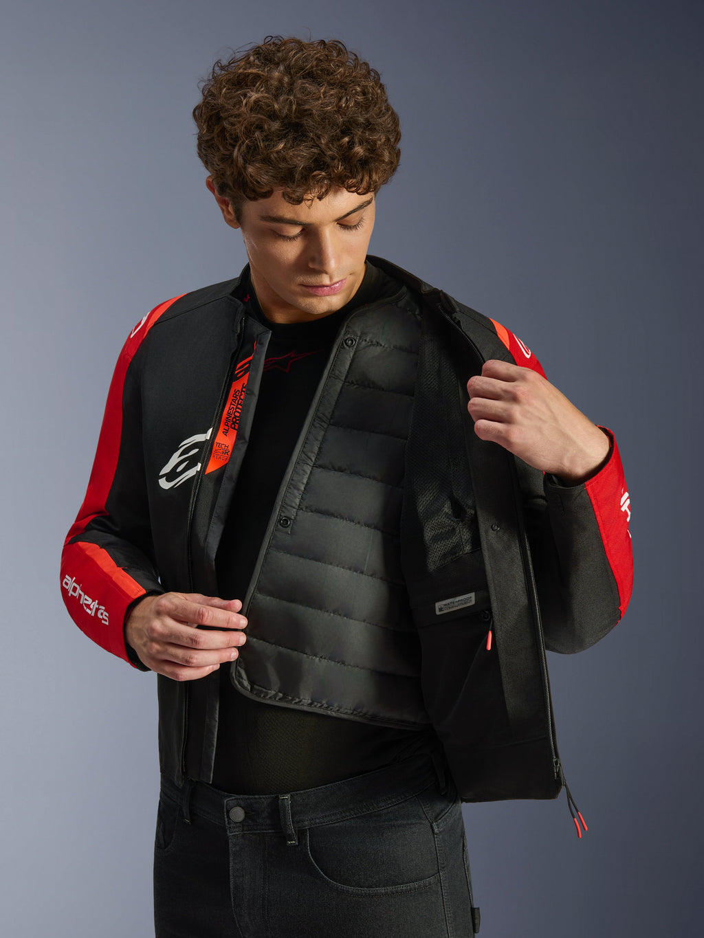 Alpinestars T-SPS V2 Waterproof Jacket, veste de moto imperméable noire et rouge, modèle montrant la doublure thermique matelassée et le compartiment étanche, marquage Tech-Air Ready, coupe sport technique