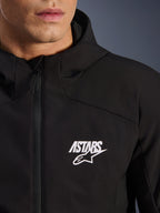 Veste Alpinestars Aeroshell Waterproof, veste de moto softshell noire, vue rapprochée de la poitrine avec logo étoile ASTARS blanc et fermeture éclair avant imperméable, capuche intégrée, design sportif moderne