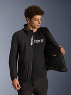 Veste Alpinestars Aeroshell Waterproof, veste de moto softshell noire, dézippée laissant apparaître la poche intérieure et la doublure, portée par un mannequin avec un t-shirt noir à logo, design à capuche pour un style urbain et décontracté.