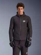Veste imperméable Alpinestars Aeroshell, noire, veste de moto urbaine, design à capuche avec fermeture éclair frontale, logos blancs sur la poitrine et les manches, portée avec un pantalon et des gants noirs assortis