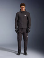 Mannequin homme portant la veste imperméable Alpinestars Aeroshell WP en noir, avec pantalon technique et gants de moto noirs assortis, design softshell à capuche avec détails de logo blancs, tenue moderne inspirée du sport moto pour la conduite sur route