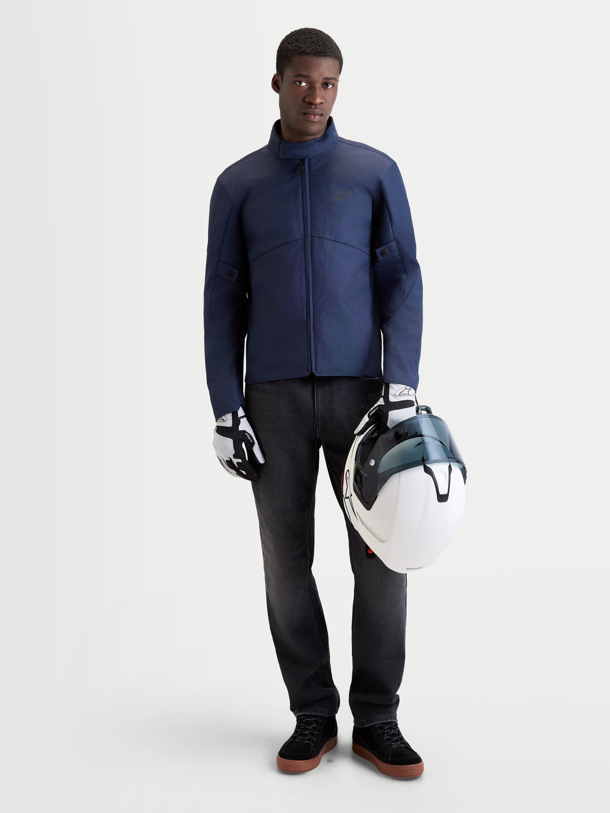 Alpinestars C 1 Waterproof Veste, veste de moto urbaine pour homme en bleu foncé, vue de face sur un modèle portant des gants assortis et tenant un casque blanc