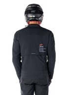 Veste Alpinestars AMT-8 Stretch Drystar® XF, vue arrière, noire, portée avec un casque et un pantalon noirs, avec le marquage Alpinestars Motion Technology au dos, design adventure touring en matériau stretch ergonomique