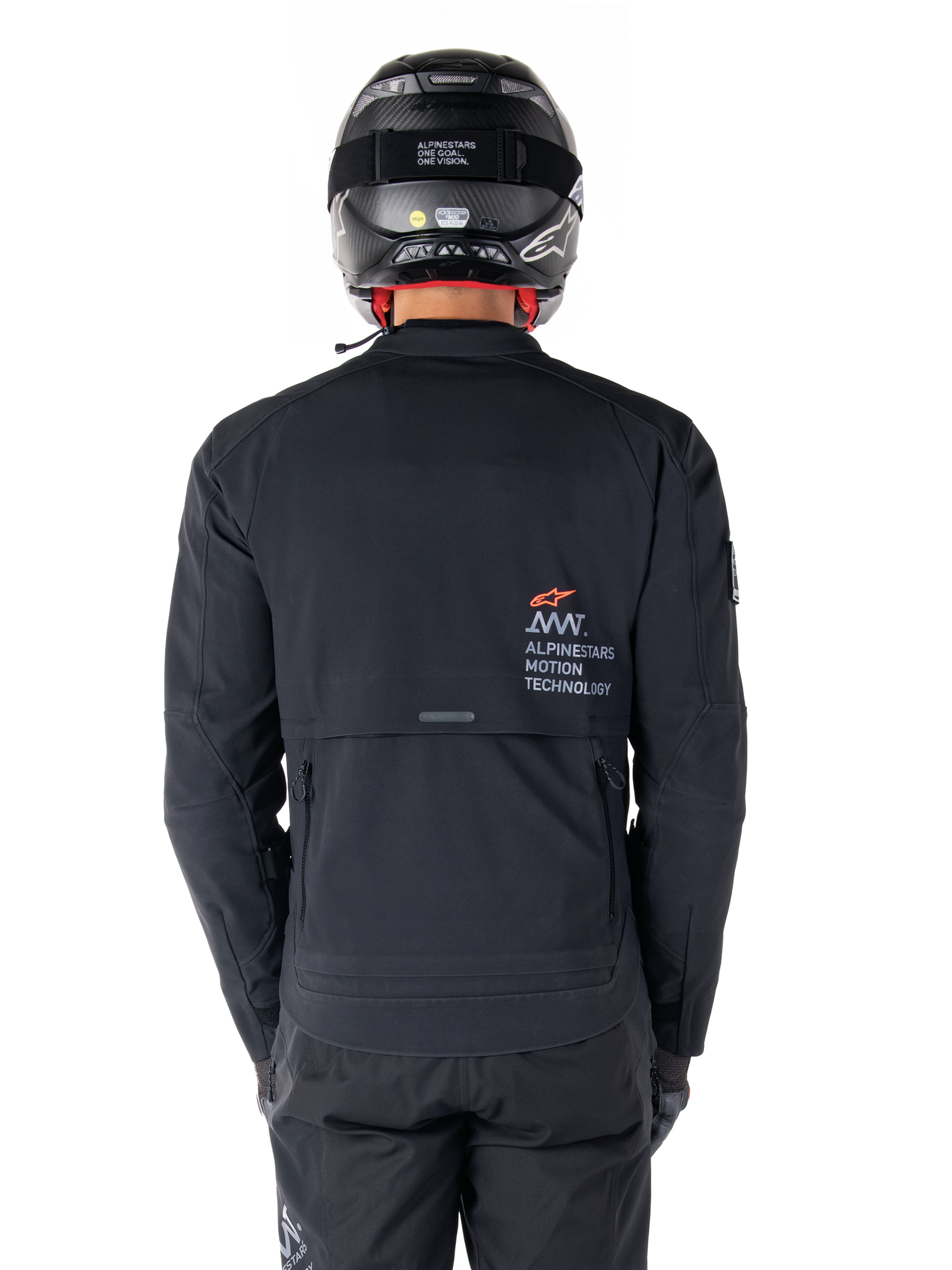 Veste Alpinestars AMT-8 Stretch Drystar® XF, vue arrière, noire, portée avec un casque et un pantalon noirs, avec le marquage Alpinestars Motion Technology au dos, design adventure touring en matériau stretch ergonomique