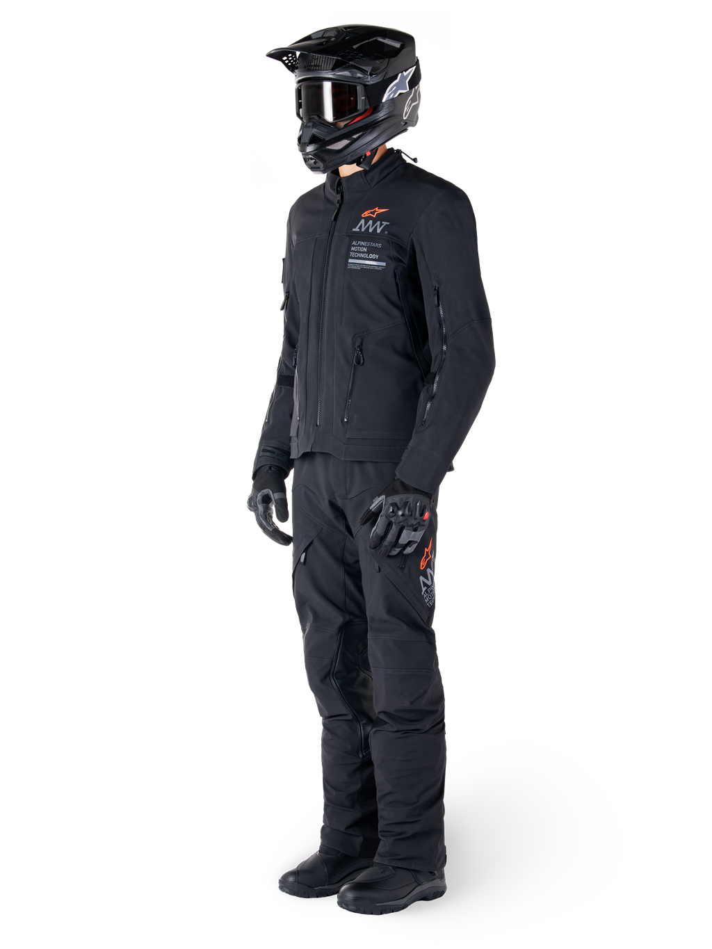 Veste Alpinestars AMT-8 Stretch Drystar® XF, veste de moto aventure, noire, portée avec pantalon, casque et gants assortis, avec marquage Alpinestars Motion Technology et accents orange, construction stretch durable pour le pilotage aventure