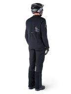Veste Alpinestars AMT-8 Stretch Drystar® XF, noire, vue arrière d'un pilote portant la veste avec un pantalon noir assorti et un casque noir, arborant le marquage « Alpinestars Motion Technology » dans le dos, matériau stretch technique pour la pratique de la moto d'aventure