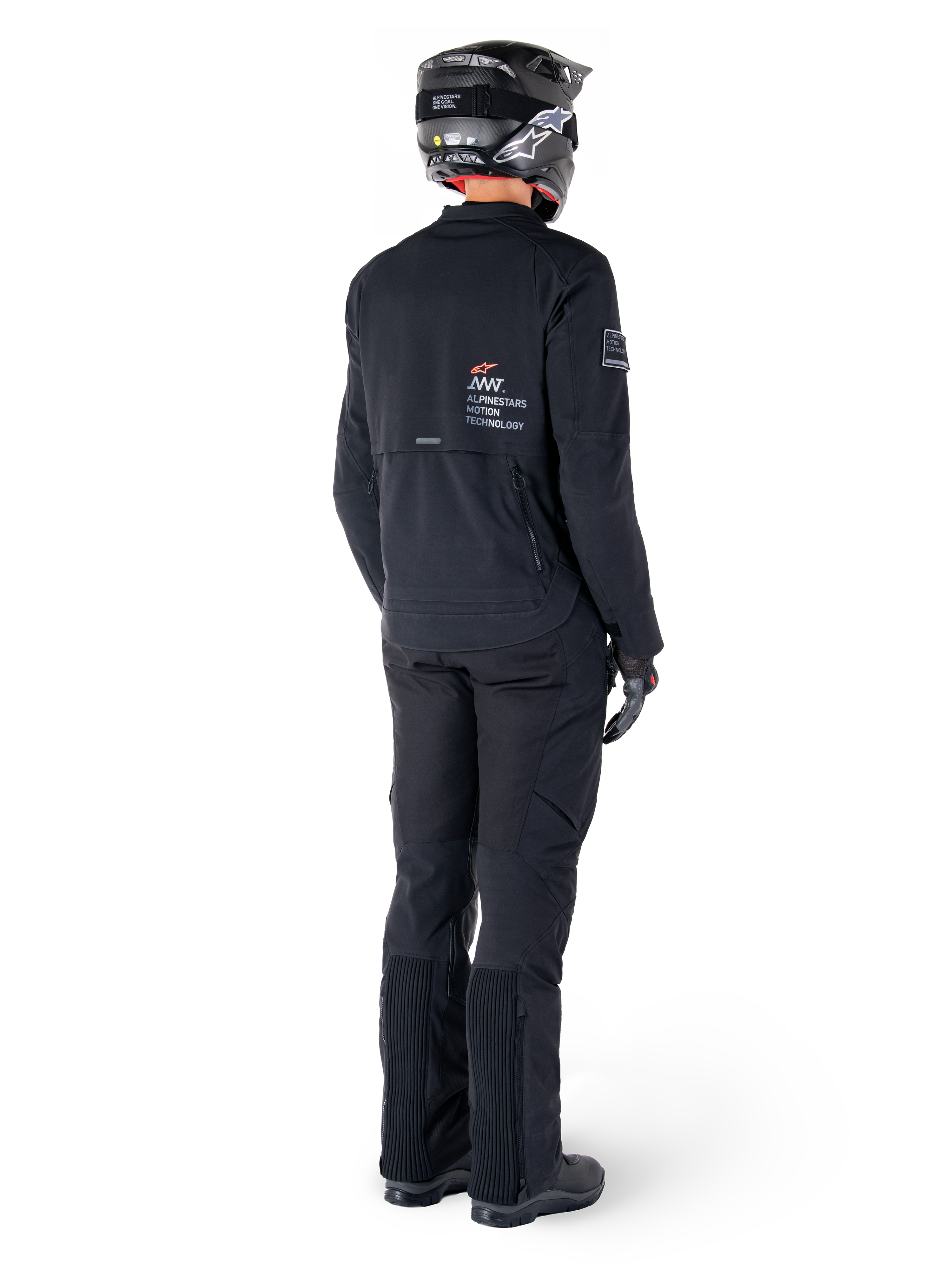 Veste Alpinestars AMT-8 Stretch Drystar® XF, noire, vue arrière d'un pilote portant la veste avec un pantalon noir assorti et un casque noir, arborant le marquage « Alpinestars Motion Technology » dans le dos, matériau stretch technique pour la pratique de la moto d'aventure