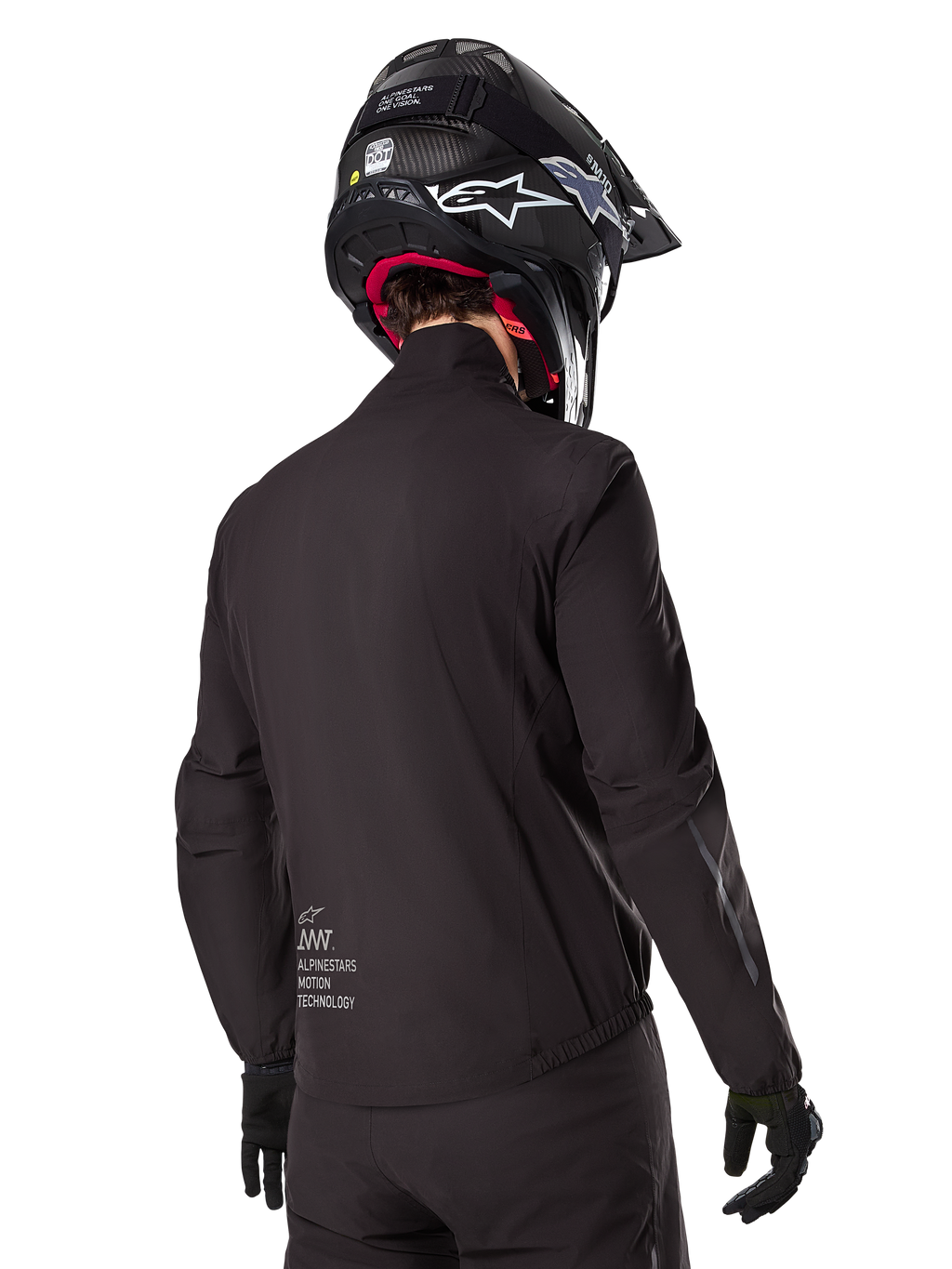 Doublure Alpinestars AMT-8 Stretch Drystar® XF, doublure de veste imperméable noire, vue arrière d'un pilote portant un casque noir et des gants, avec le marquage Alpinestars Motion Technology sur le bas du dos, design minimaliste et fonctionnel pour la conduite aventure.