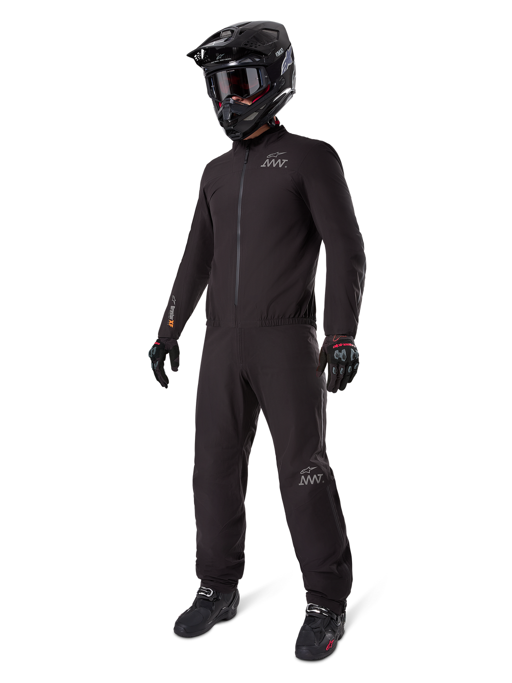 Doublure Alpinestars AMT-8 Stretch Drystar® XF, combinaison de moto imperméable noire, portée avec un casque noir, des lunettes et des gants, arborant les logos AMT et Drystar XF, équipement d'aventure fonctionnel pour une protection par tous les temps.