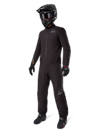 Doublure Alpinestars AMT-8 Stretch Drystar® XF, combinaison de moto imperméable noire, portée avec un casque noir, des lunettes et des gants, arborant les logos AMT et Drystar XF, équipement d'aventure fonctionnel pour une protection par tous les temps.