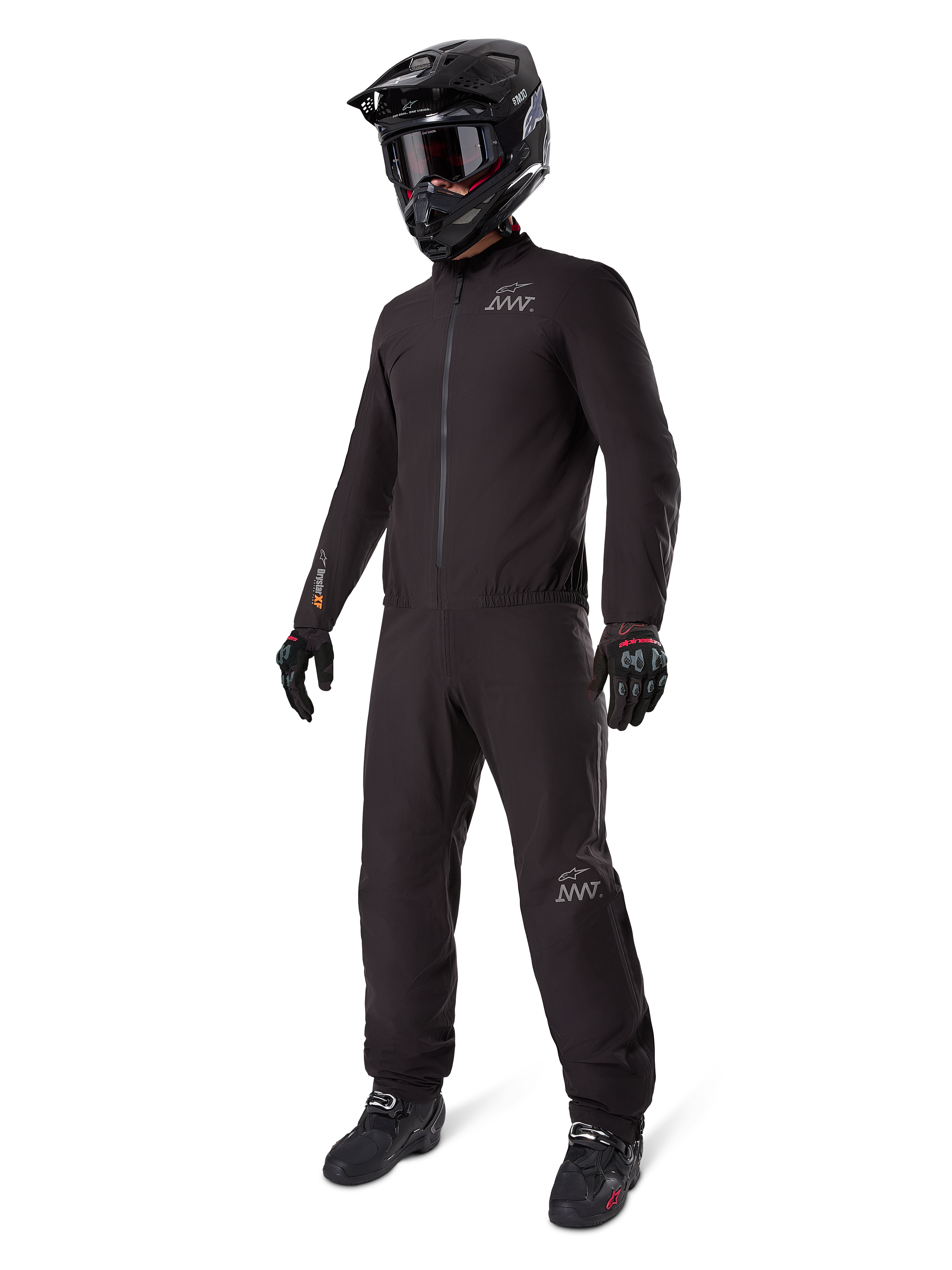 Doublure Alpinestars AMT-8 Stretch Drystar® XF, combinaison de moto imperméable noire, portée avec un casque noir, des lunettes et des gants, arborant les logos AMT et Drystar XF, équipement d'aventure fonctionnel pour une protection par tous les temps.