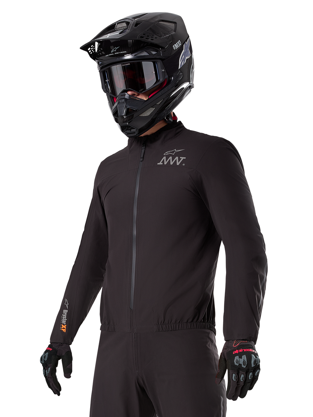 Pilote portant la doublure Alpinestars AMT-8 Stretch Drystar® XF, veste stretch noire coupe-vent et imperméable, arborant le logo AMT sur la poitrine et le marquage Drystar XF sur la manche, associée à un casque d'aventure noir et des gants de protection.