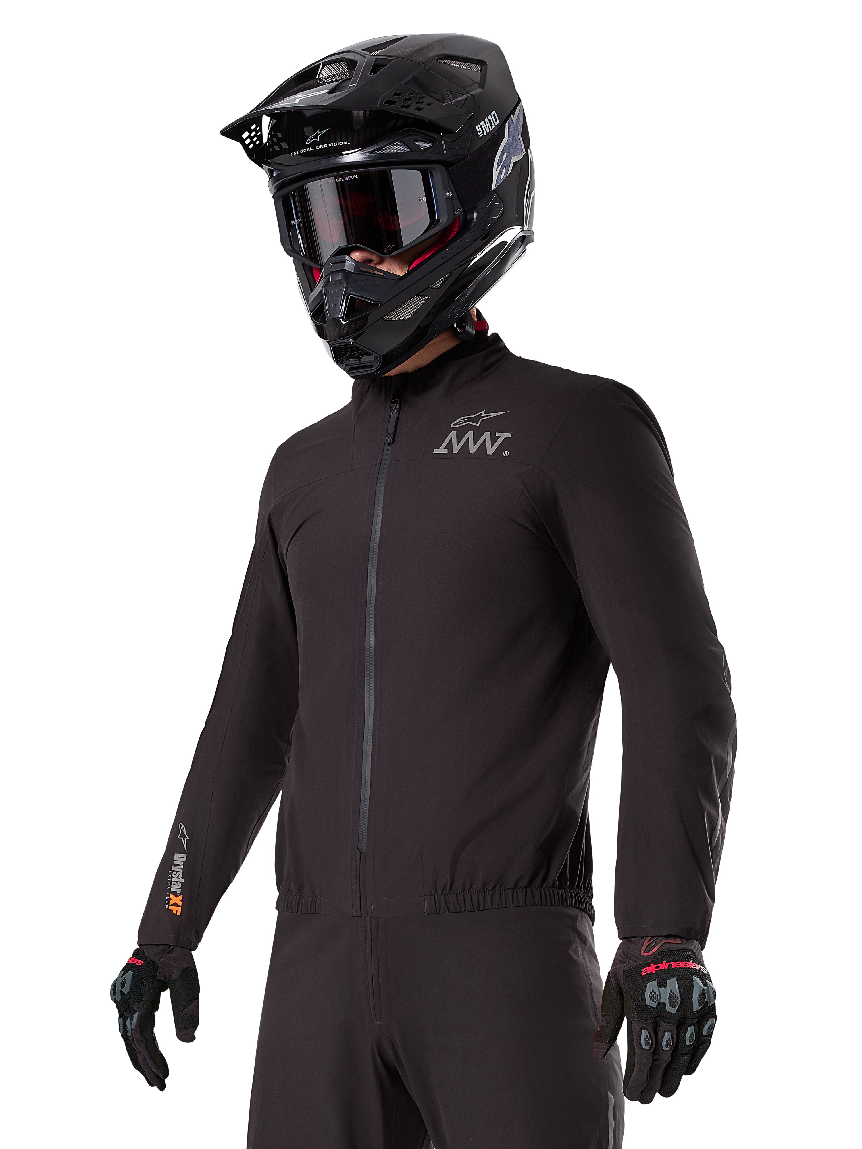 Pilote portant la doublure Alpinestars AMT-8 Stretch Drystar® XF, veste stretch noire coupe-vent et imperméable, arborant le logo AMT sur la poitrine et le marquage Drystar XF sur la manche, associée à un casque d'aventure noir et des gants de protection.