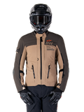 Veste Alpinestars AMT-8 Stretch Drystar XF, veste de moto d'aventure touring, kaki foncé et marron foncé, avec logo Astars orange et fermetures éclair noires, portée avec un casque d'aventure noir et des gants noirs, tenue de moto complète
