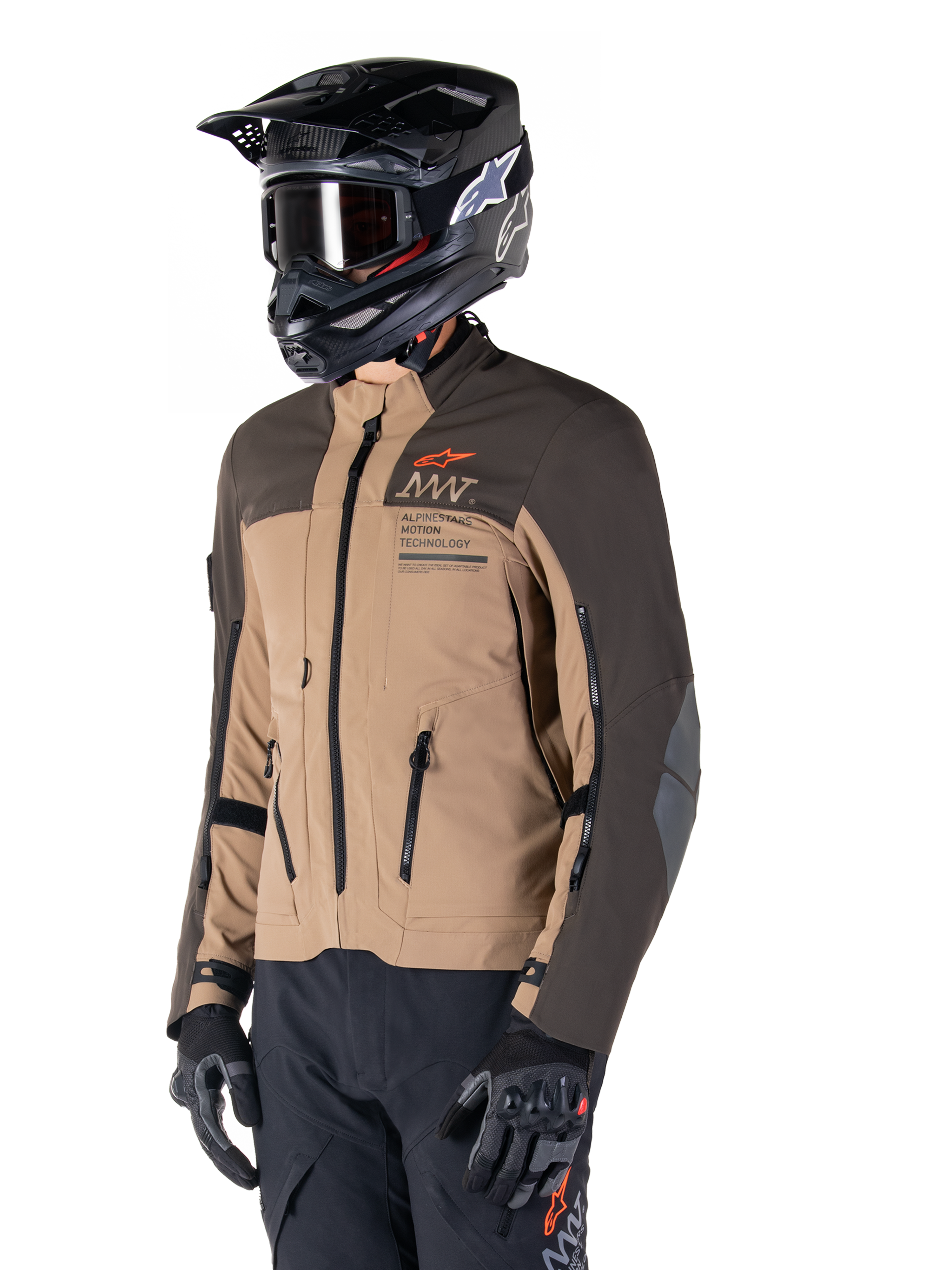 Veste Alpinestars AMT-8 Stretch Drystar® XF, veste de moto d'aventure, brun foncé et kaki foncé, portée avec un casque tout-terrain noir et des lunettes, arborant le marquage Alpinestars Motion Technology et des ouvertures de ventilation zippées.
