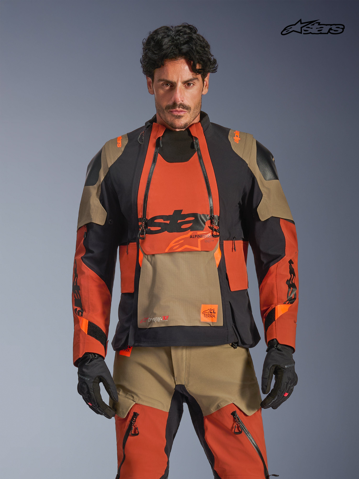 Alpinestars Veste Laminée Halo Pro Drystar® XF, veste de moto adventure pour homme en coloris marron, rouille et noir, vue de face sur un modèle portant l'équipement assorti, avec une construction textile imperméable et des panneaux de ventilation modulaires