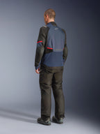 Veste Alpinestars Andes V4 Drystar®, Night Navy et Mood Indigo avec empiècements noirs et accents rouges, vue de dos de trois-quarts, portée avec un pantalon de moto d'aventure et des bottes noirs assortis, construction en textile technique avec logo Alpinestars sur le haut du dos, ourlet arrière allongé pour une meilleure protection.
