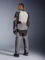 Veste Alpinestars Andes V4 Drystar®, gris foncé et gris glacier avec accents noirs et rouge vif, vue arrière montrant un panneau gris clair avec logo étoile rouge, associée à un pantalon d'aventure assorti et des gants noirs, équipement technique de moto toutes saisons