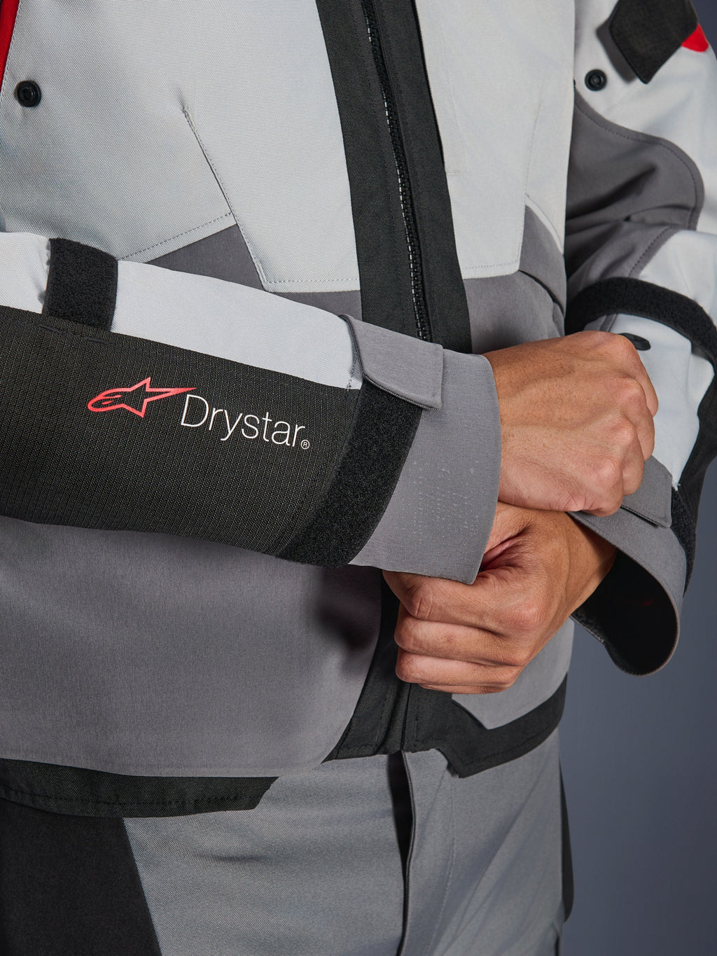 Détail de la manche de la veste Alpinestars Andes V4 Drystar®, textile gris et noir, logo Drystar rouge et blanc sur l'avant-bras, fermeture de poignet réglable par velcro, équipement de moto imperméable haute performance