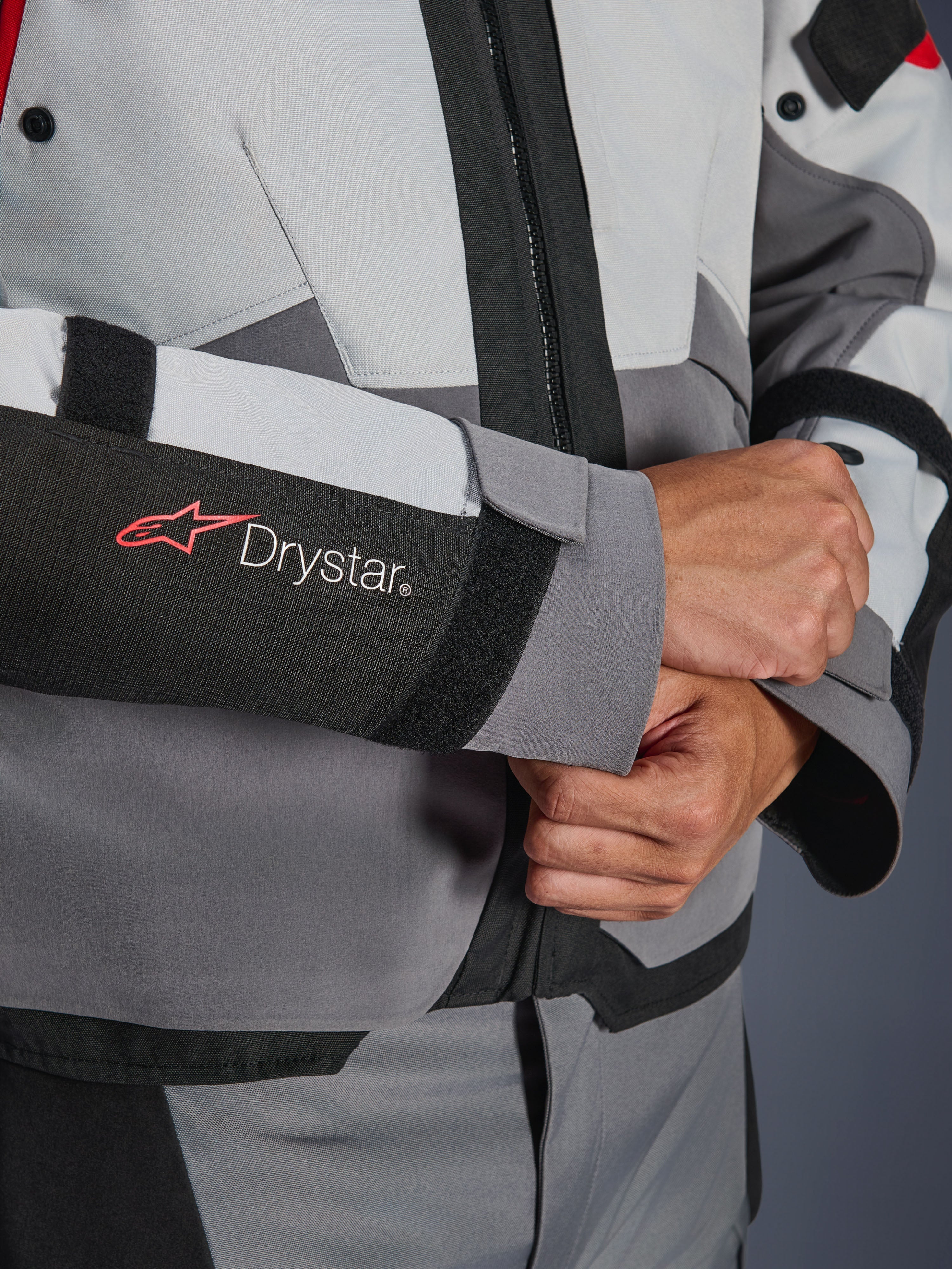 Détail de la manche de la veste Alpinestars Andes V4 Drystar®, textile gris et noir, logo Drystar rouge et blanc sur l'avant-bras, fermeture de poignet réglable par velcro, équipement de moto imperméable haute performance