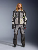 Male model with long blonde hair wearing the Andes V4 Drystar® Jacket in Dark Gray, Ice Gray, Black, and Yellow Fluo, paired with matching adventure motorcycle pants and black boots, full technical riding outfit for all-weather touring.