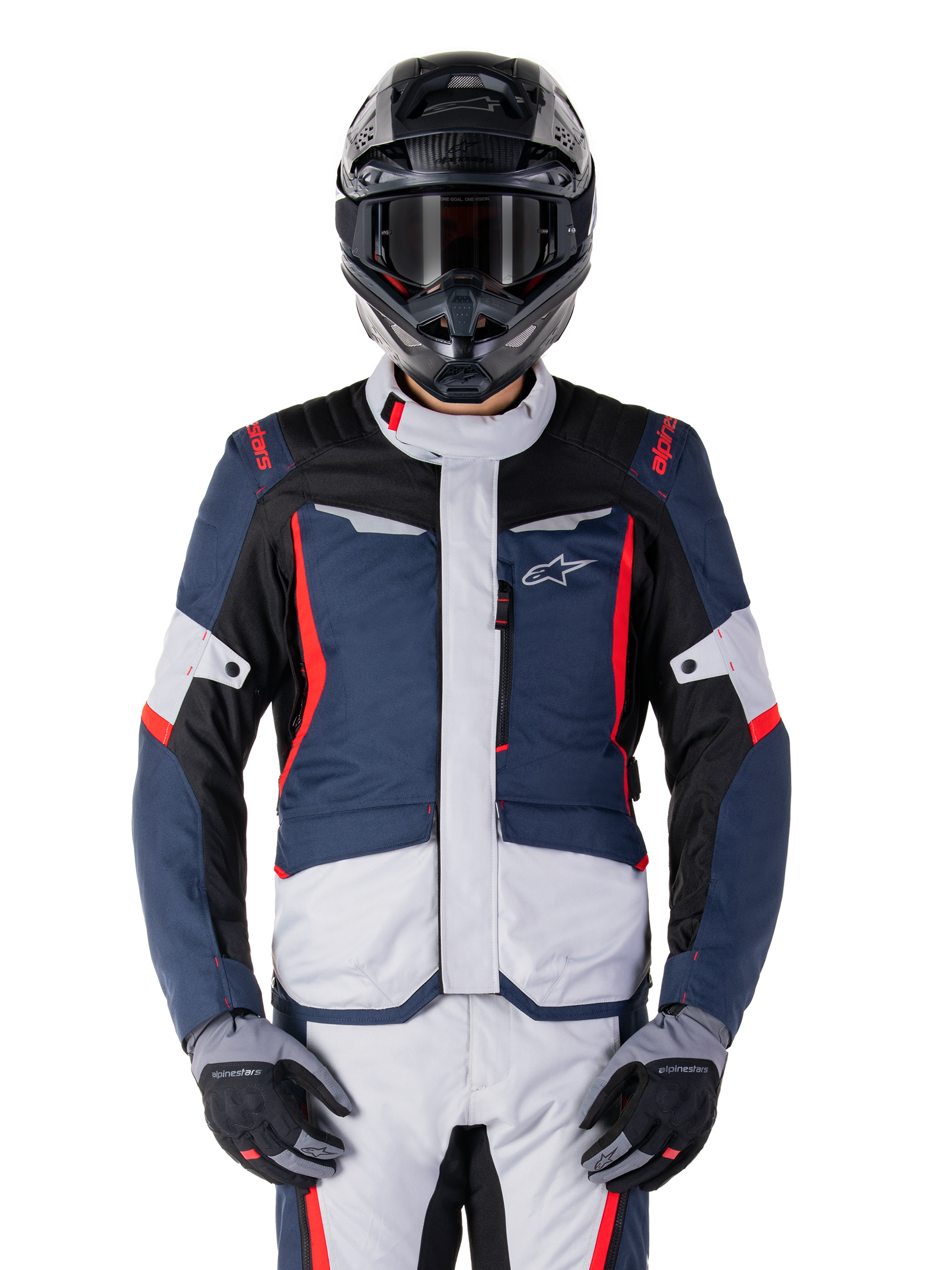 Veste imperméable Alpinestars ST-1, veste de moto de tourisme d'aventure, bleu foncé et noir avec panneaux gris clair et accents rouge vif, portée avec un pantalon assorti et un casque noir, arborant le logo étoile sur la poitrine et une construction textile durable