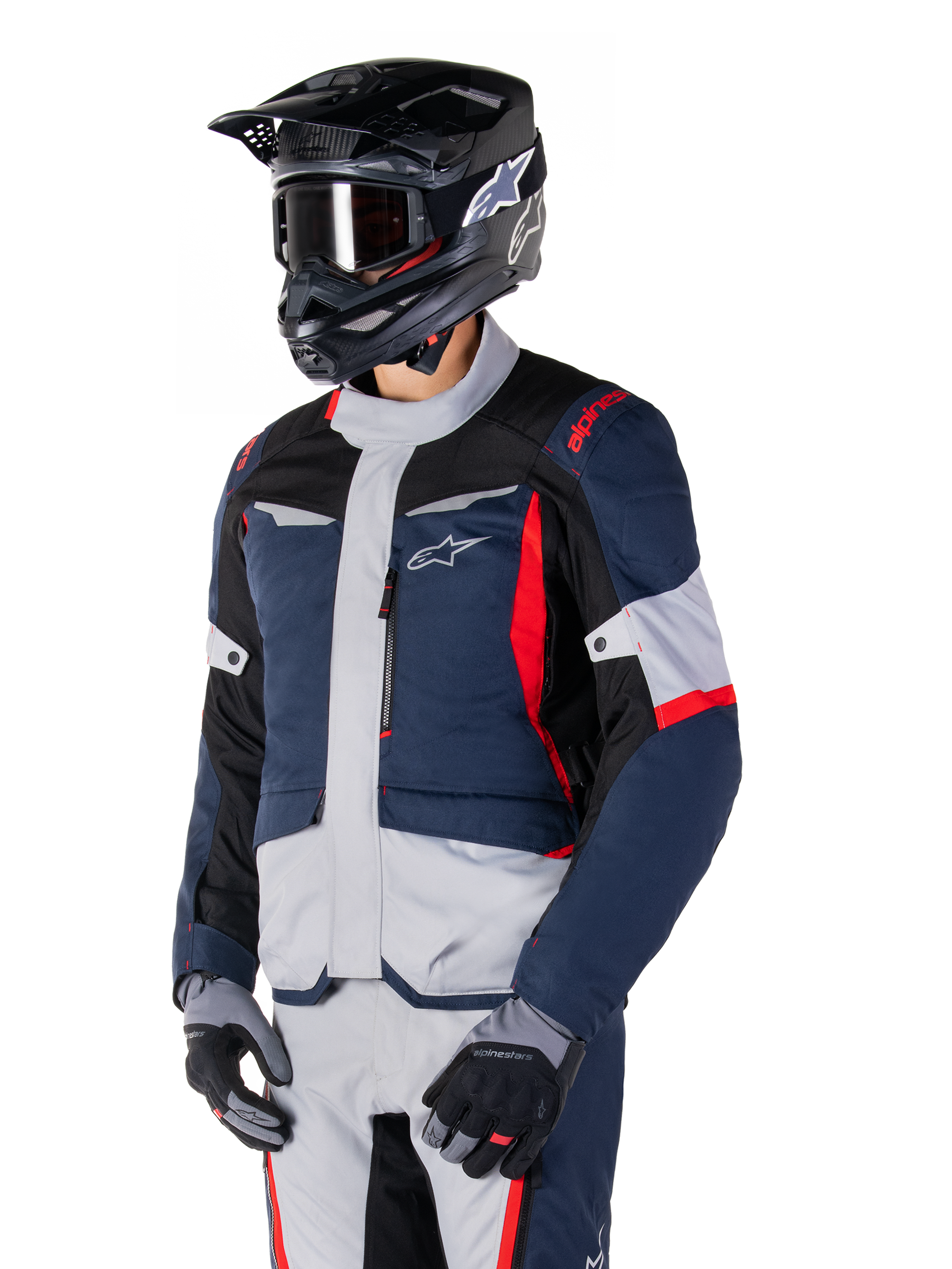 Veste Alpinestars ST-1 Waterproof, veste de moto d'aventure touring en bleu foncé, noir et rouge vif, portée avec un casque noir et des gants gris, dotée d'un design moderne avec des poches fonctionnelles et le logo Alpinestars.