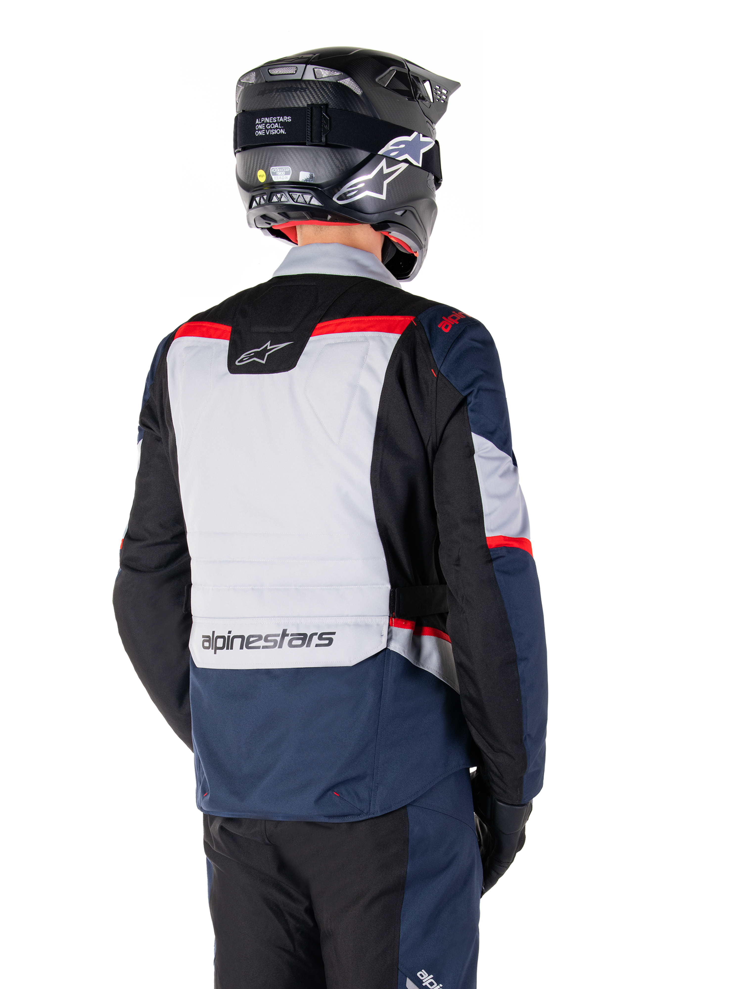 Veste imperméable Alpinestars ST-1, bleu foncé, noir et rouge vif, vue arrière d'un pilote portant un casque d'aventure noir, avec des panneaux gris clair et le marquage Alpinestars, équipement de moto adventure touring