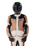 Veste imperméable Alpinestars ST-1, Dark Khaki Sand Black Red Fluo, portée par un pilote avec un casque et des gants noirs, équipement de touring aventure avec empiècements beige et marron et accents rouge fluo vifs, vue de face sur fond blanc.
