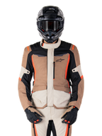 Veste imperméable Alpinestars ST-1, Dark Khaki Sand Black Red Fluo, portée par un pilote avec un casque et des gants noirs, équipement de touring aventure avec empiècements beige et marron et accents rouge fluo vifs, vue de face sur fond blanc.