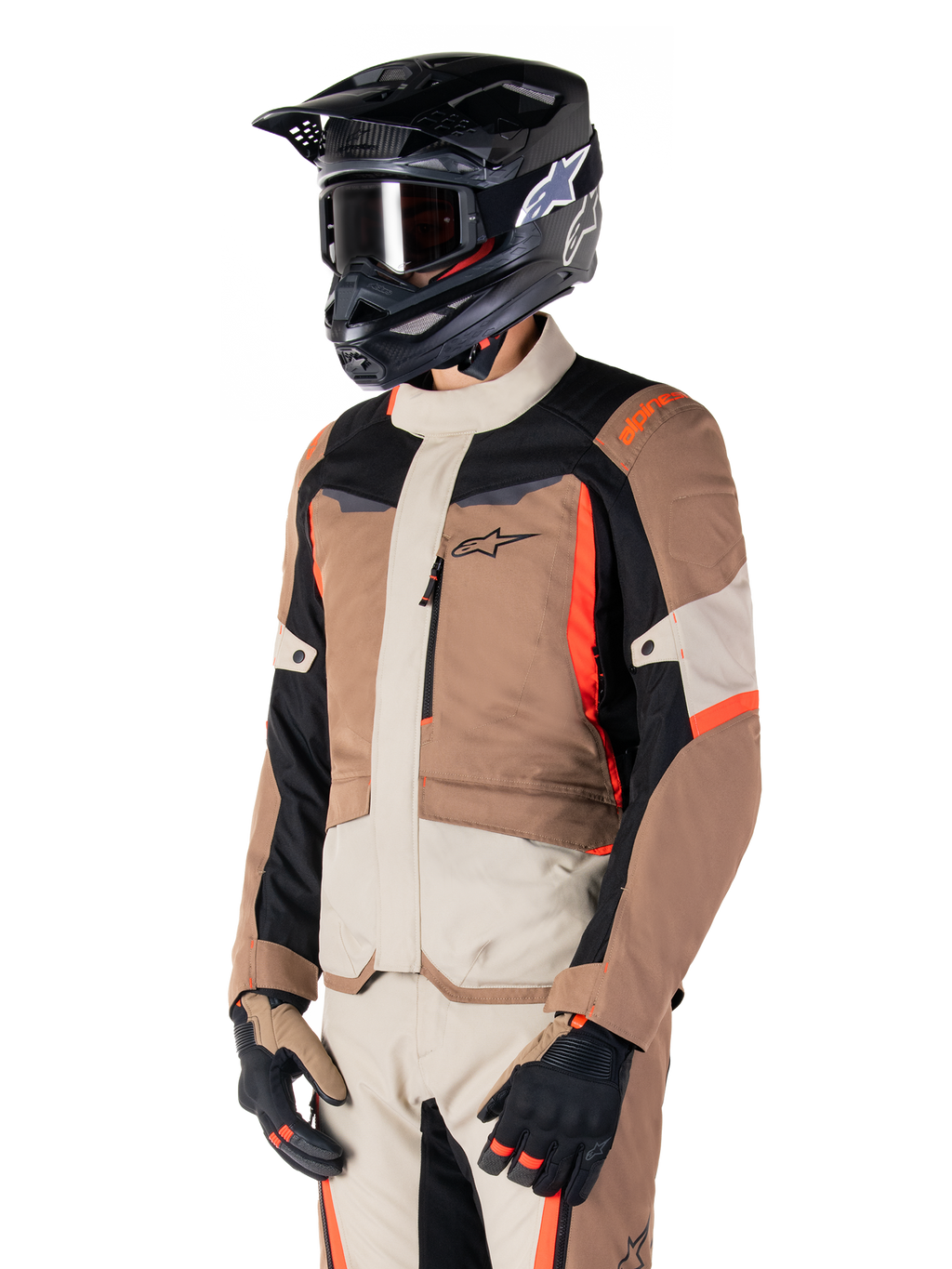 Veste imperméable Alpinestars ST-1, veste de touring aventure, kaki foncé, sable, noir et rouge fluo, portée par un motard avec un casque de motocross noir et des lunettes, dotée d'une conception multi-panneaux avec des poches cargo et le logo Alpinestars sur la poitrine
