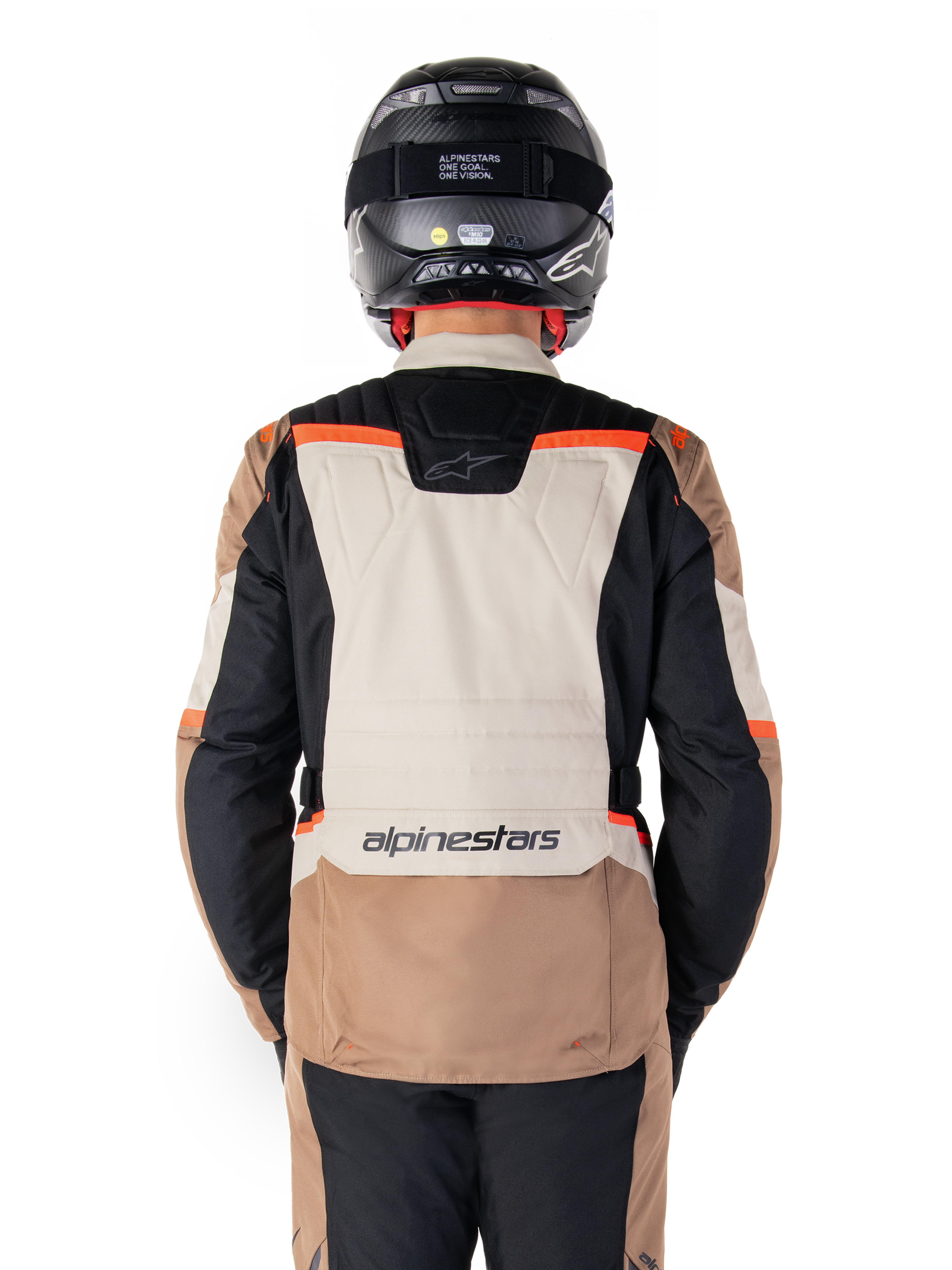 Veste imperméable Alpinestars ST-1, Dark Khaki Sand Black Red Fluo, vue arrière, veste de moto aventure touring dotée d'un large panneau dorsal couleur sable, de manches noires et d'accents rouge fluo, portée par un motard avec un casque noir.