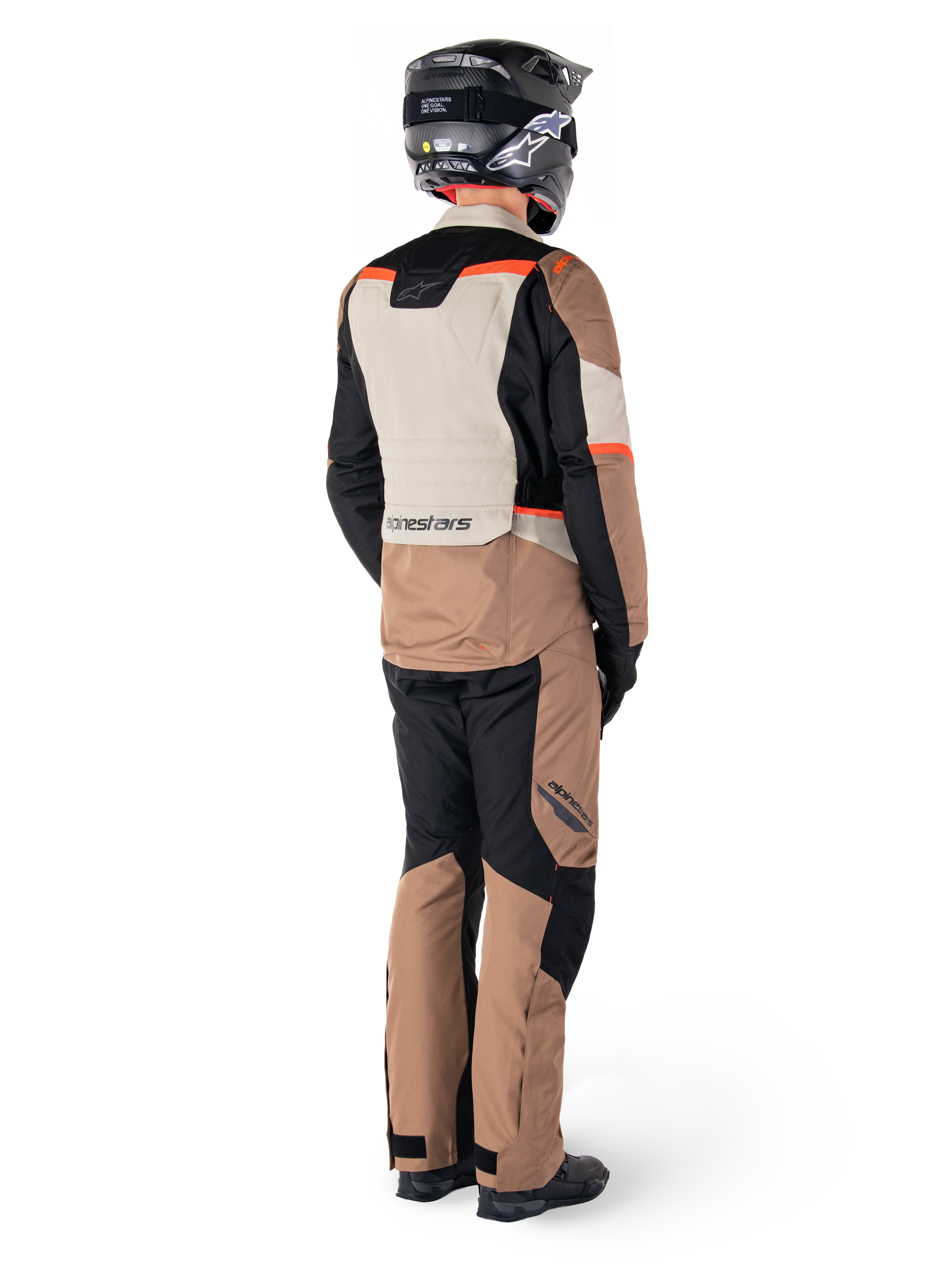 Veste imperméable Alpinestars ST-1, veste de touring aventure, kaki foncé, sable, noir et rouge fluo, vue arrière portée avec un pantalon assorti et un casque noir, avec des panneaux color-block et des accents rouges fluorescents.