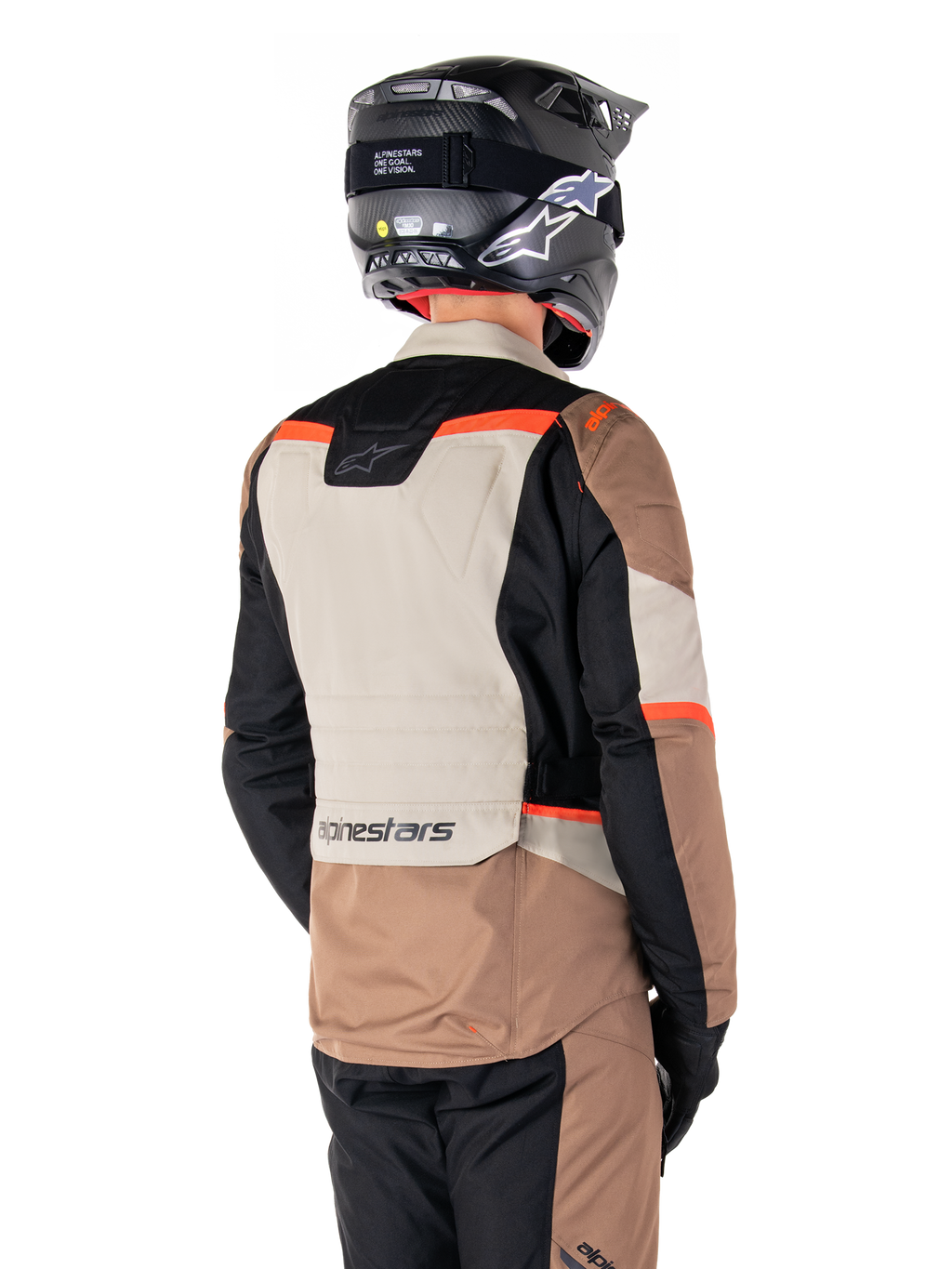 Veste imperméable Alpinestars ST-1, veste d'aventure touring, Dark Khaki Sand Black Red Fluo, vue arrière montrant des empiècements textiles color-block, des accents rouge fluo et le marquage Alpinestars dans le bas du dos, portée par un motard avec un casque noir.