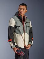 Veste imperméable Alpinestars Mospher en Fur Gray Black Ice, parka textile multi-panneaux avec sections grises, noires et blanc cassé, accents de fermetures éclair et sangles rouge vif, design d'inspiration tactique avec capuche et poches utilitaires, portée par un mannequin tenant des gants de moto.
