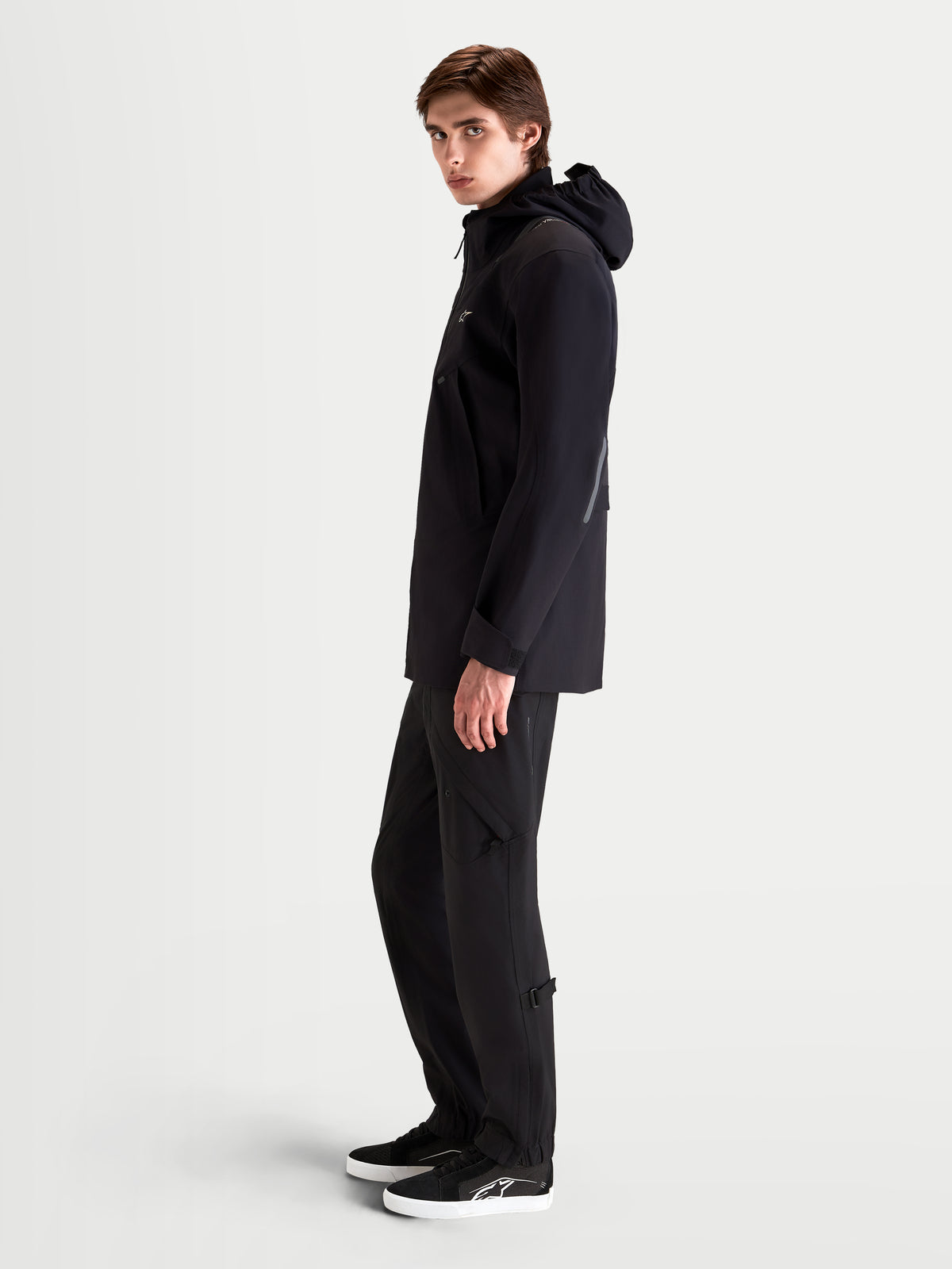 Alpinestars C 7 Drystar XF Veste, veste de moto urbaine contemporaine pour homme noire, vue de profil sur un modèle portant un équipement de moto assorti avec capuche intégrée
