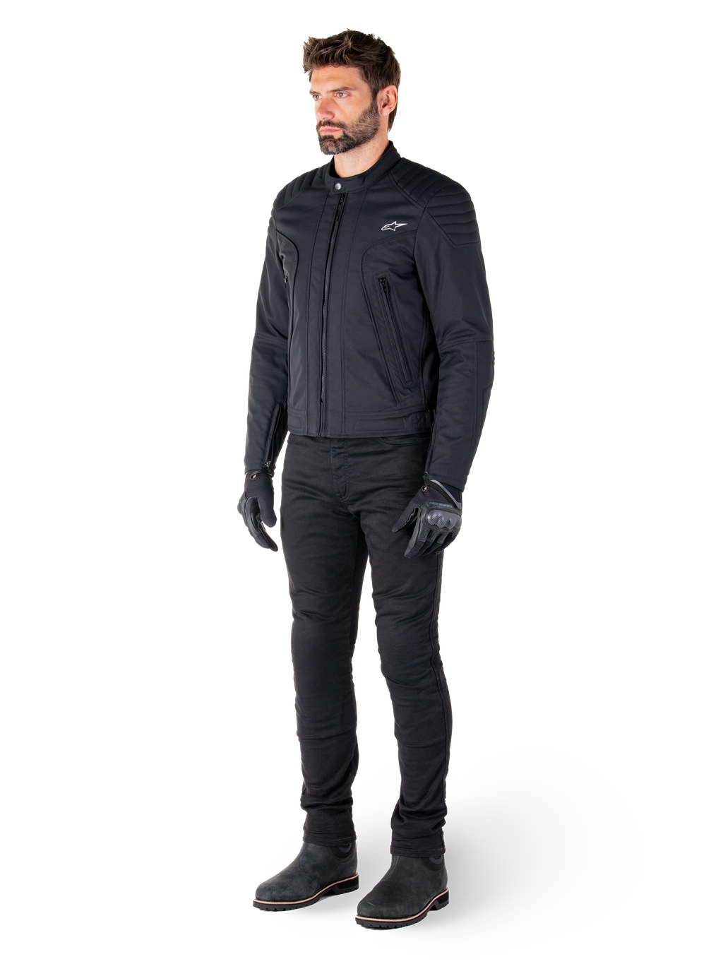Male rider wearing the Alpinestars Clayton WR Jacket, Black urban motorcycle jacket, slim-fit design with quilted shoulder accents and matte finish, paired with black technical riding pants and gloves.