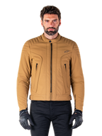 Alpinestars Clayton WR Jacket, veste de moto urbaine, Utility Brown Light Gold, textile déperlant avec épaules matelassées et rembourrées, col motard montant, détails de fermetures éclair noires et logo sur la poitrine, portée avec des gants de protection et un pantalon noirs