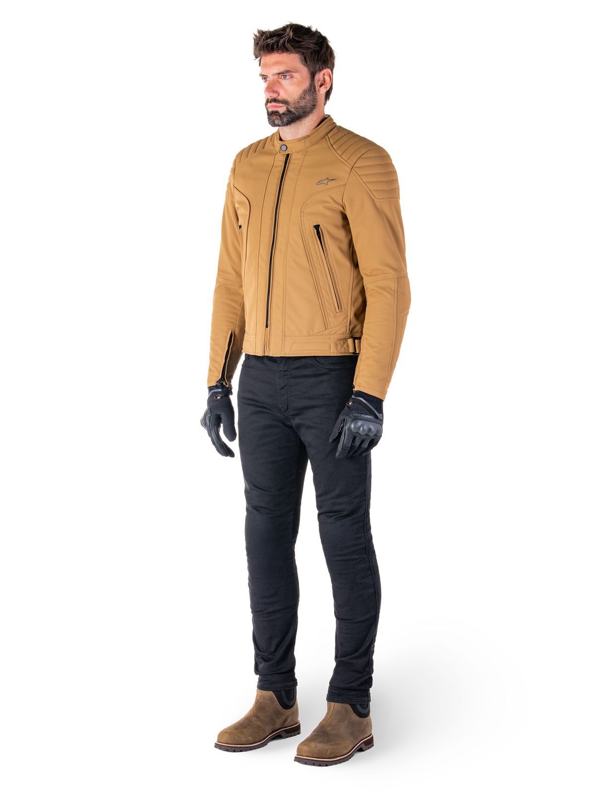 Motard portant la veste Alpinestars Clayton WR en Utility Brown Light Gold, veste de moto urbaine contemporaine avec détails matelassés aux épaules, associée à un pantalon noir, des gants noirs et des bottes marron