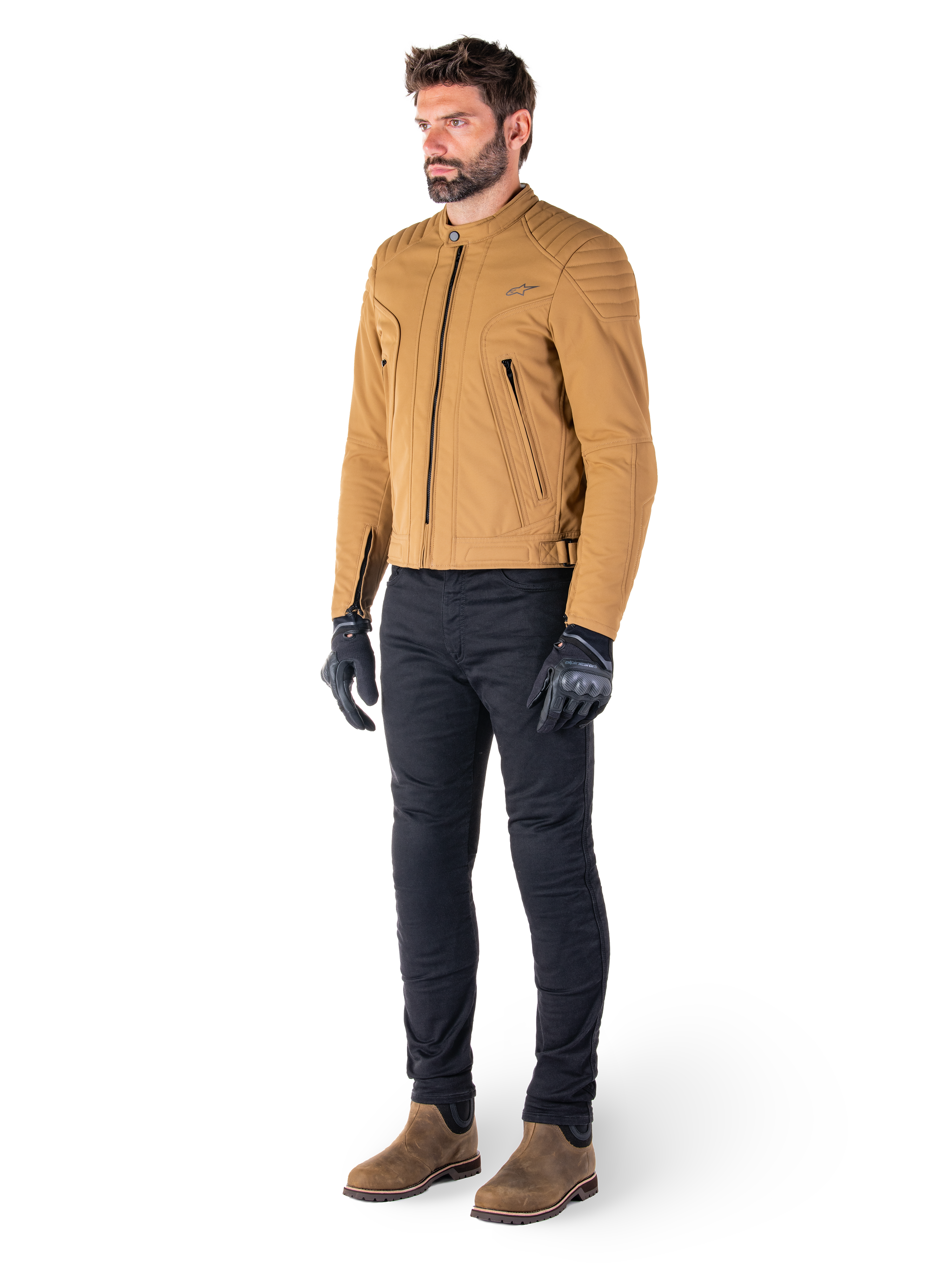 Motard portant la veste Alpinestars Clayton WR en Utility Brown Light Gold, veste de moto urbaine contemporaine avec détails matelassés aux épaules, associée à un pantalon noir, des gants noirs et des bottes marron