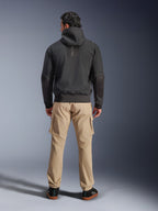 Veste imperméable Alpinestars Moblast, noir, vue arrière d'un hoodie de moto urbain, porté avec un pantalon cargo beige et des baskets noires, design minimaliste avec marquage vertical « astars » sur le haut du dos, équipement de conduite contemporain toutes saisons
