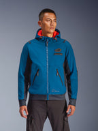 Veste imperméable Alpinestars Moblast portée par un mannequin, bleu et bleu marine foncé, veste de moto urbaine, design à capuche avec doublure intérieure rouge, fermetures éclair noires et détail de patch sur la poitrine, équipement de moto d'inspiration streetwear