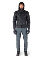 Veste Alpinestars Mohobbs Waterproof noire, mannequin portant un blouson aviateur matelassé à capuche, associé à un pantalon de moto gris, des gants noirs et des bottes noires, équipement de moto urbain contemporain