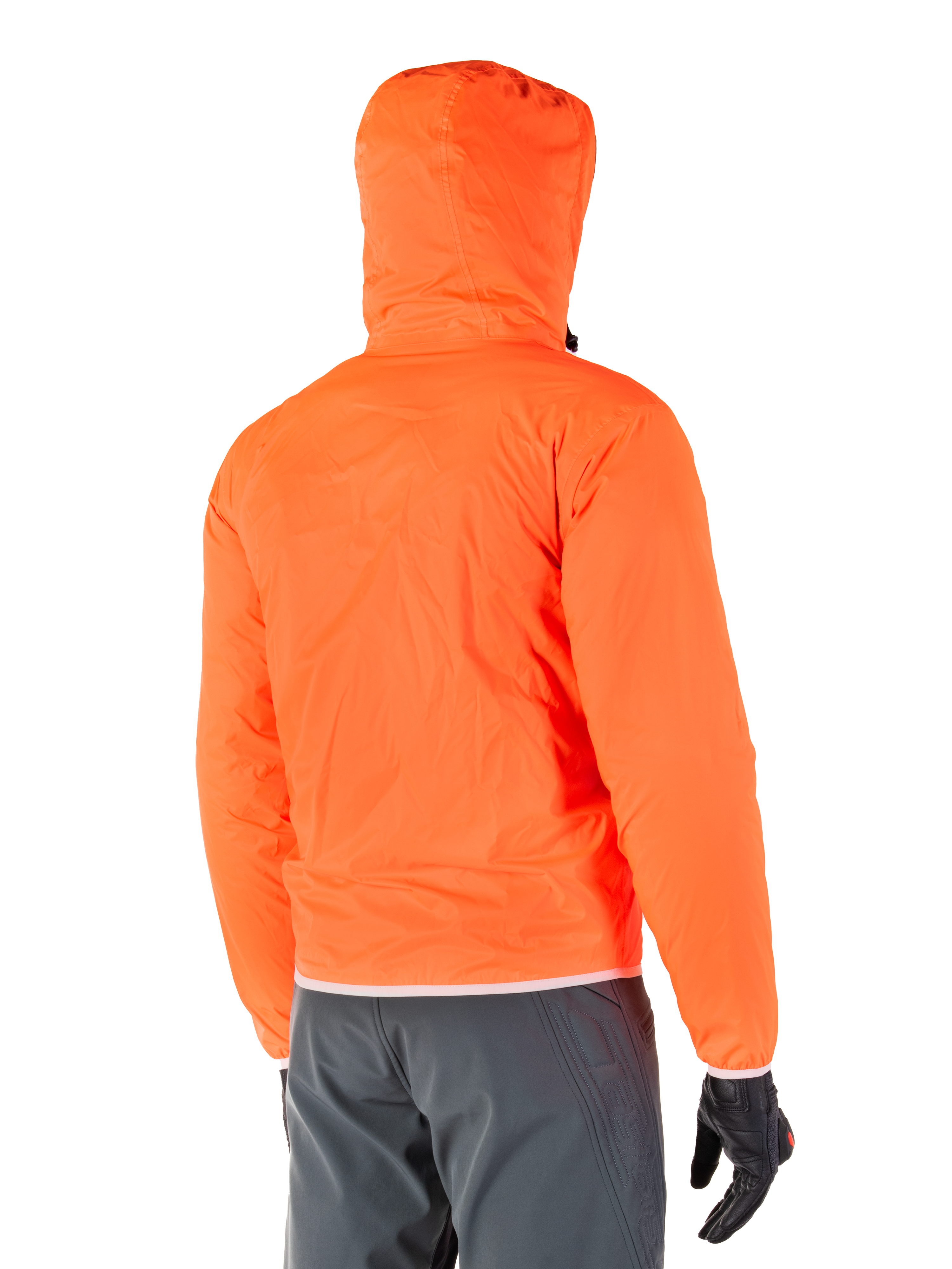 Veste Mohobbs Waterproof d'Alpinestars, doublure de pluie d'urgence compressible de couleur orange fluo éclatant, vue arrière montrant la capuche anti-tempête, portée avec un pantalon de moto gris foncé et des gants noirs, équipement de moto urbain léger et imperméable