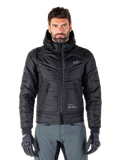 Veste Alpinestars Mohobbs Waterproof, blouson aviateur de moto rembourré noir, tissu poly matelassé avec fermeture éclair centrale et poches zippées, petit logo blanc sur la poitrine, porté par un mannequin avec un pantalon gris et des gants, design streetwear urbain pour la conduite en ville.